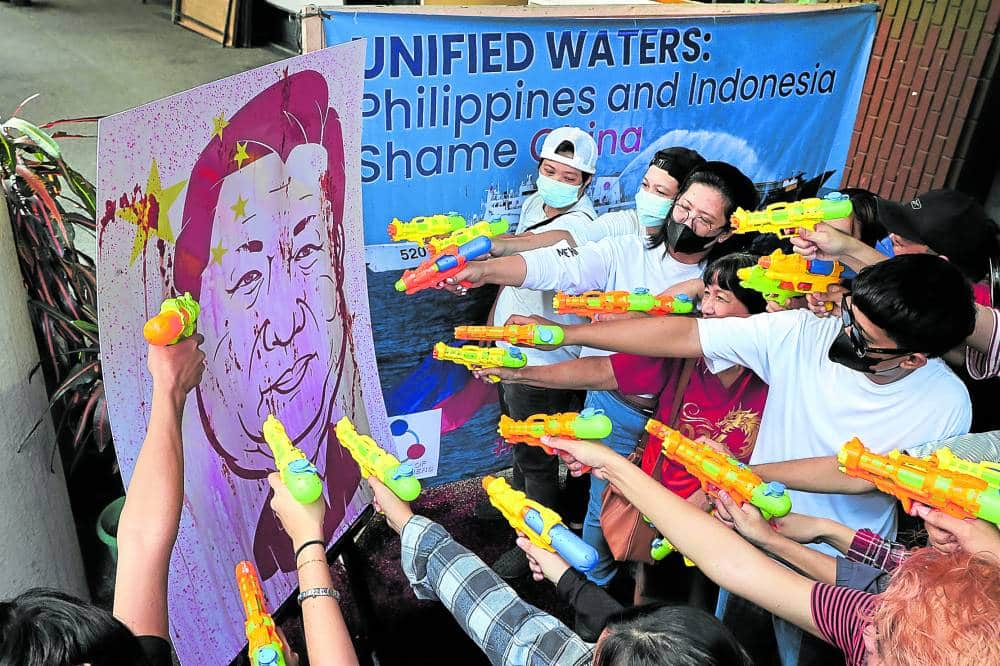 ‘WATER CANNON’ TARGET Members of the Alliance of West Philippine Sea Watchers subject an image of Chinese President Xi Jinping to a symbolic water cannon attack during a forum in Quezon City on Tuesday. Defense Secretary Gibo Teodoro spoke of more reasons for them to pull the trigger.